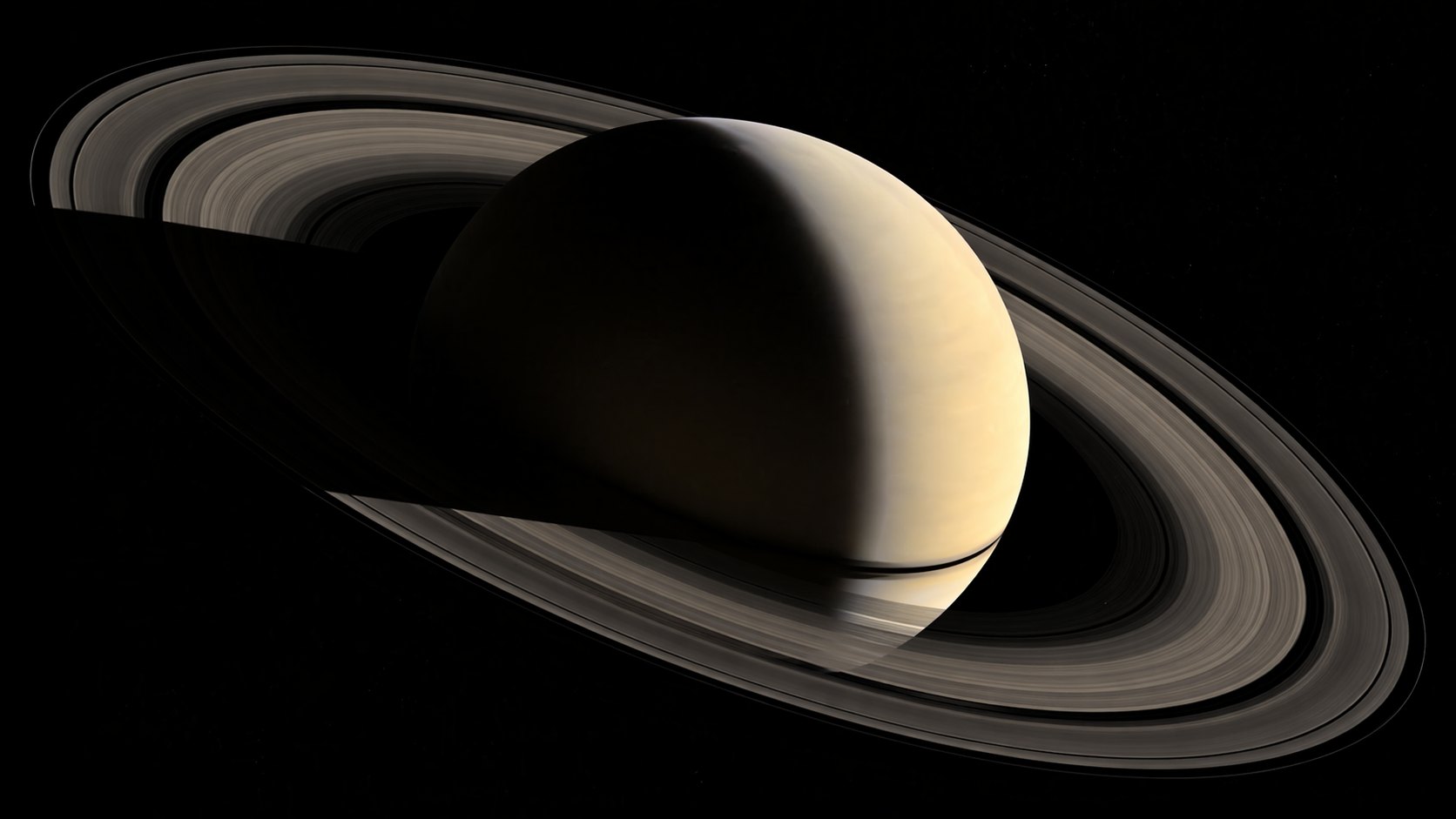 Saturn w fazie sierpa z widocznymi pierścieniami i ich cieniem padającym na atmosferę planety