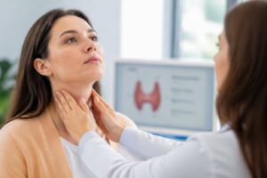 Kobieta dotykająca szyi w okolicach tarczycy podczas badania